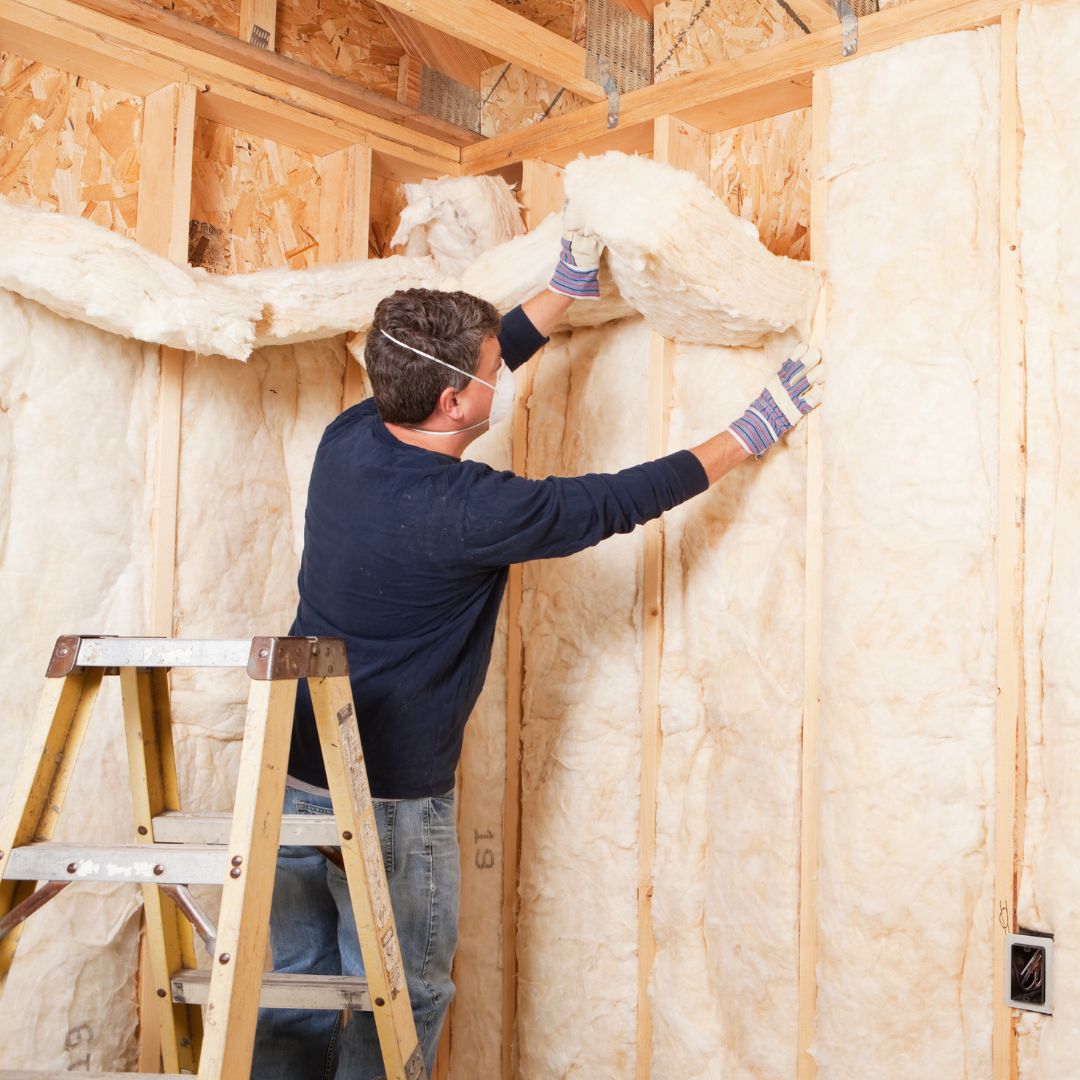 Construction Worker Insulating Wall with Fiberglass Batt