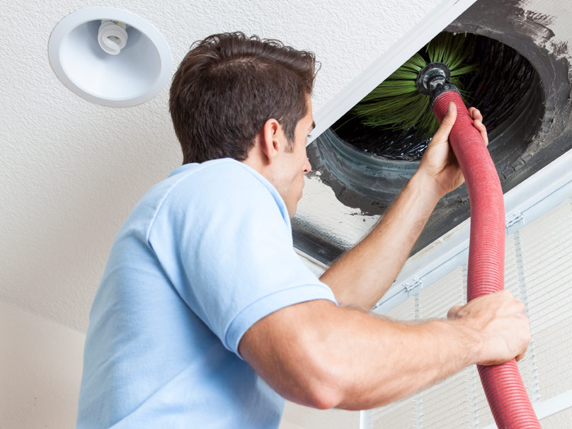 man cleaning air duct vacuum