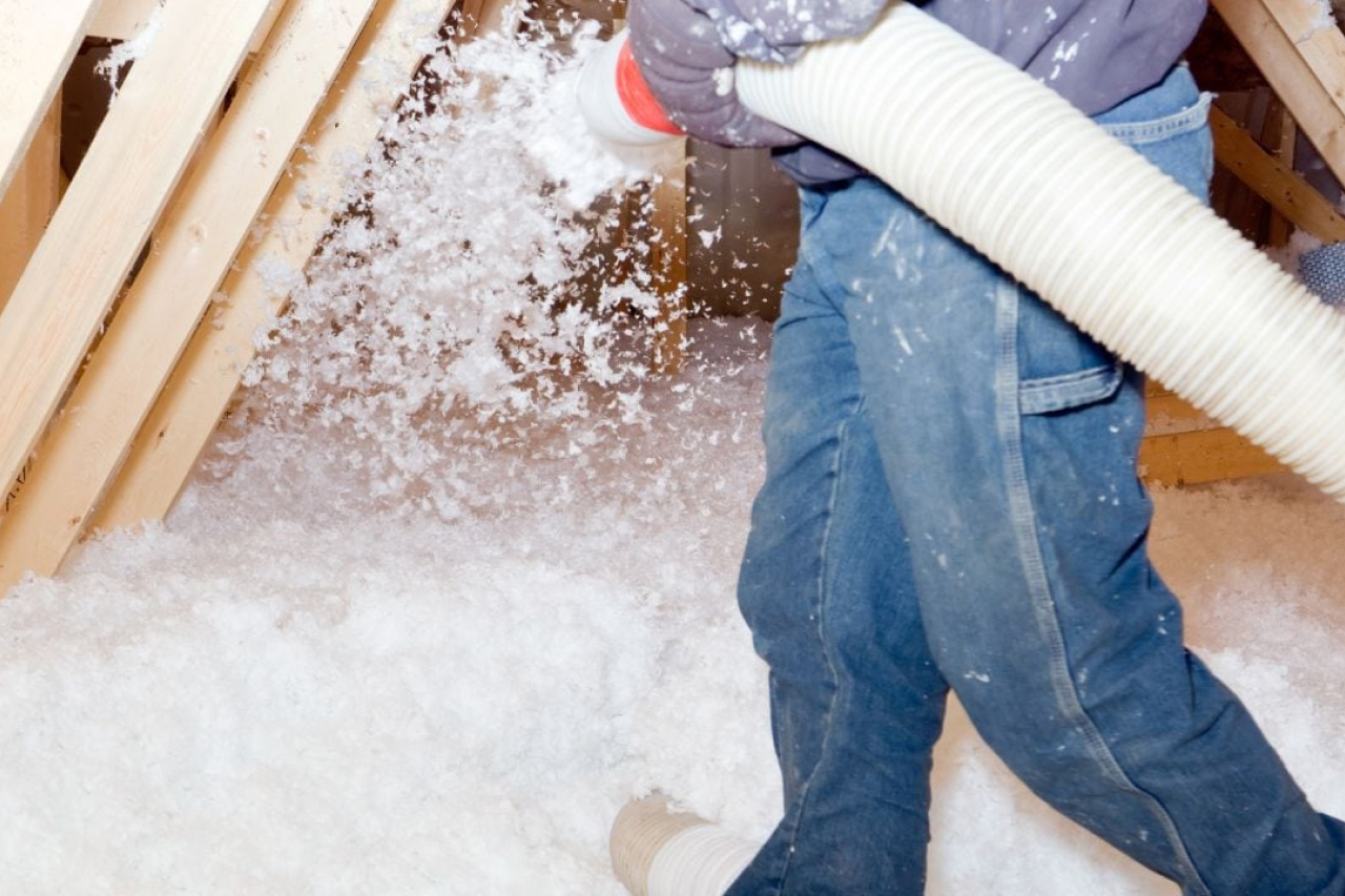 a man using blown in insulation in the attic